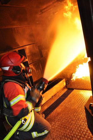 Ein Feuerwehrmann versucht das Feuer in der Brandsimulationsanlage zu löschen.