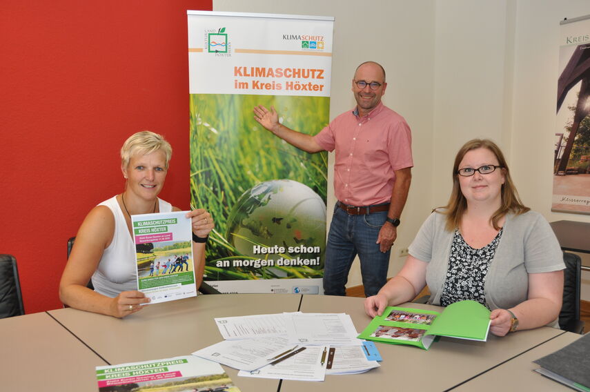 Michael Werner, Dr. Kathrin Weiß und Carolin Röttger werben vor einem Rollbanner für den Klimaschutzpreis.