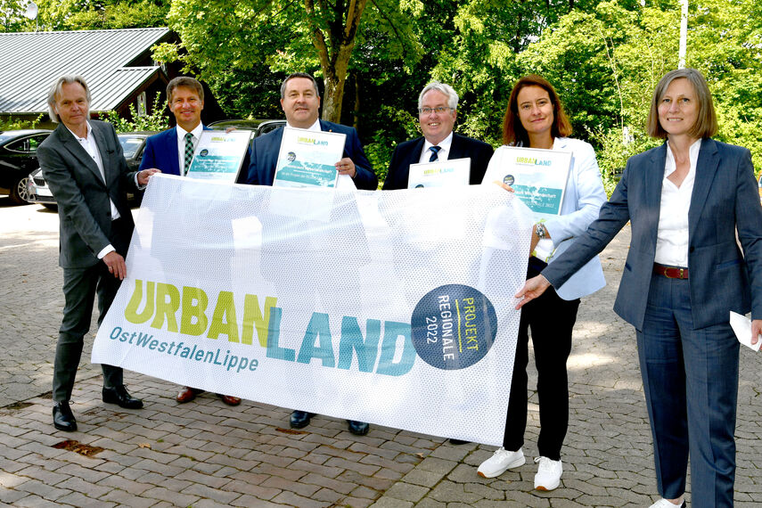 6 Personen halten einen Banner in der Hand mit der Aufschrift: 'Urban Land Ostwestfalen Lippe'.