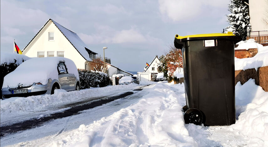 Mülltonne in schneebedeckter Straße.