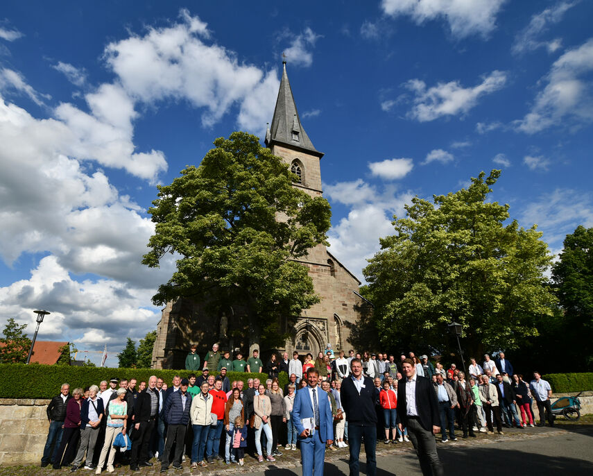 Teilnehmer von der Dorfbegehung stehen vor einer Kirche.