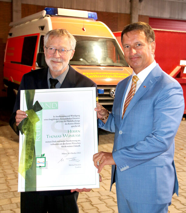 Landrat Michael Stickeln überreicht Pater Thomas Wunram als Leiter der Feuerwehr- und Notfallseelsorge im Kreis Höxter eine Urkunde zur Verabschiedung.